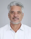 Dan-trujillo Professional Headshot of a Middle-aged Man with Gray Hair and a White Shirt Against a Light Gray Background.