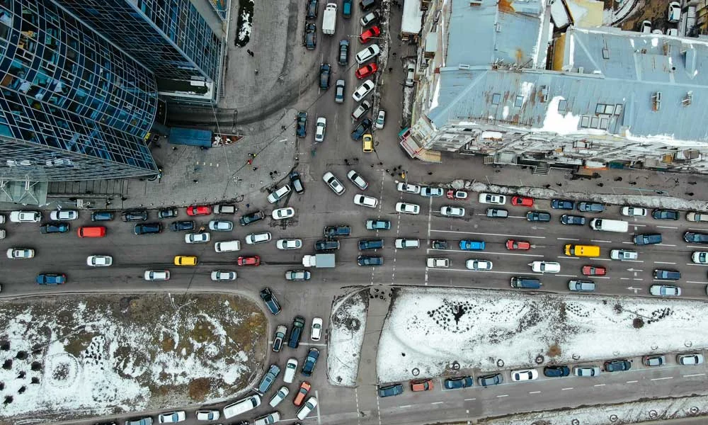 Aerial View of a Busy City Intersection with Cars Lined Up Along Snow-dusted Streets Between Tall Buildings.