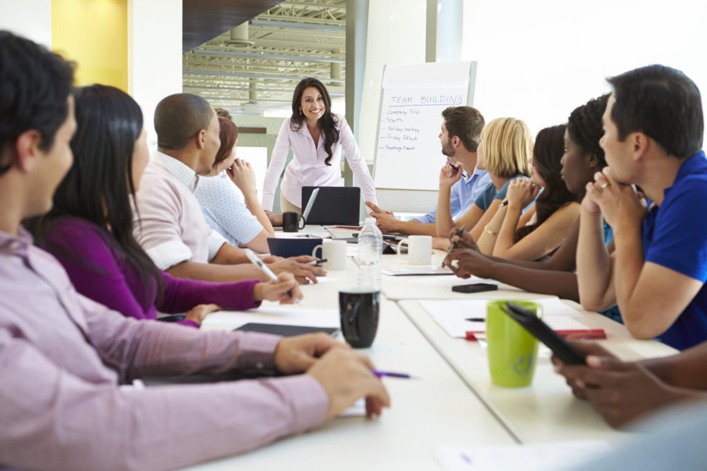 Businesswoman Addressing Meeting Around Boardroom Table