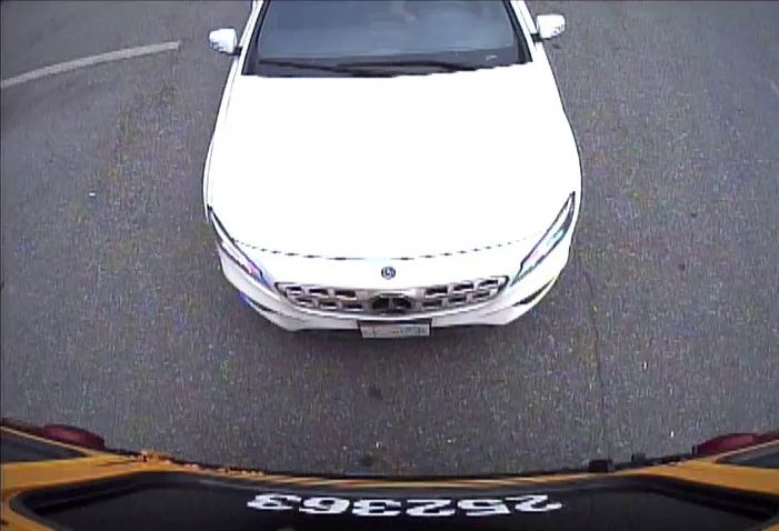 Rvc402 | Safe Fleet Front View of a White Sedan Seen from Above, Captured by a Dashcam; License Plate Not Readable in a Parking Lot.